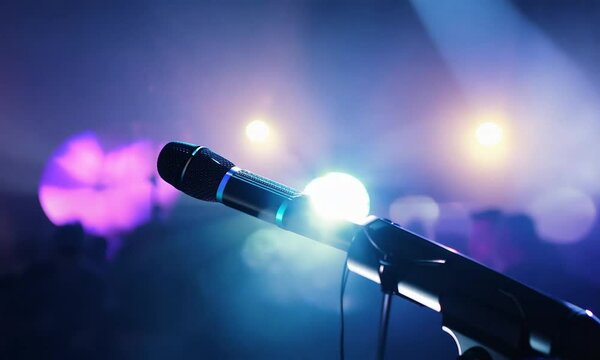 The microphone lies on the stage against the background of a concert show, performance or karaoke. Dynamic background color bokeh. The concept of a musical instrument