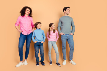 Happy family standing together against beige background, showcasing casual style and warm expressions