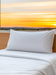 Crisp white pillow and bedding on a bed, showcasing a vibrant sunset view