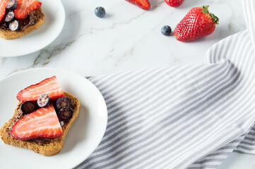 Fresh toasts with chocolate paste and berries serve for delicious breakfast. Spreading sweet...