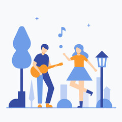 A man and a woman are playing music together. The man is playing a guitar and the woman is dancing. The scene is set in a park with trees and buildings in the background