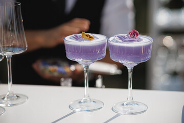 Two vibrant purple cocktails are elegantly sitting on a white table