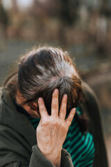An elderly woman shows off her grey hair on her dyed brown hair.