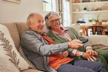 Smiling and joyful senior couple watching television at home