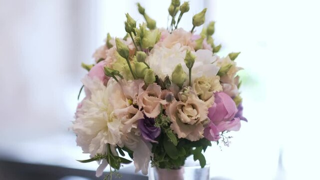 Elegant bouquet of pastel flowers with peonies and lisianthus in a glass vase on a soft blurred background