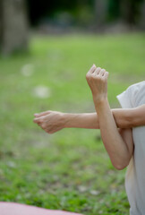 Young Asian woman doing yoga in the garden. Relaxing and healthy lifestyle concept.