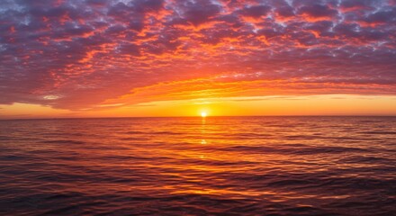 Fototapeta premium Vibrant sunset over calm ocean waters with colorful clouds reflecting on the surface
