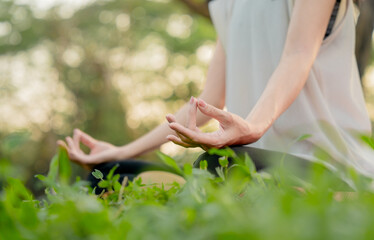 Young Asian woman doing yoga in the garden. Relaxing and healthy lifestyle concept.