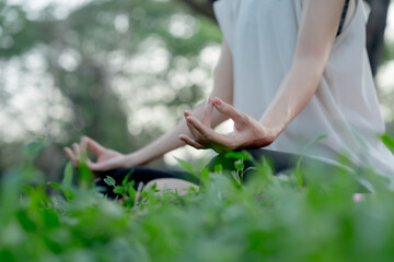 Young Asian woman doing yoga in the garden. Relaxing and healthy lifestyle concept.