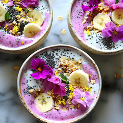 A deliciously vibrant selection of smoothie bowls made with acai, banana, dragon fruit, and coconut milk, finished with granola, chia seeds, and stunning edible flowers for a fresh appeal.