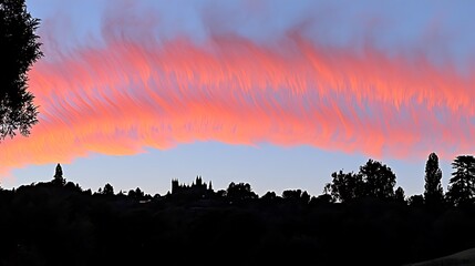 Beautiful sunset clouds over a dark silhouette of trees and buildings