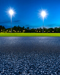 Night scene of a well-lit grassy field with asphalt foreground