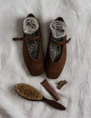 Brown suede women's shoes, socks, comb, cosmetics on a light background, top view