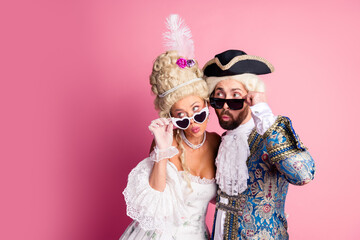 Royal themed couple in vintage costumes posing humorously on pink
