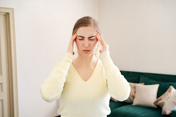 Female having dizziness holding hands on forehead at home. Tired woman with closed eyes feeling...