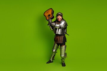 Naklejka premium Funny knight in antique armor playing a guitar against a green background