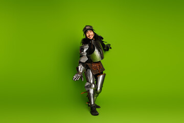 Fototapeta premium Man dressed as a medieval knight on a vibrant green backdrop posing joyfully