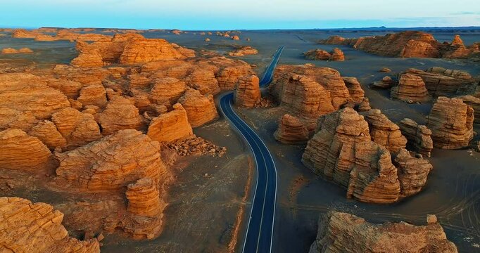 Aerial view of winding road through spectacular yardang landform in Xinjiang at sunset