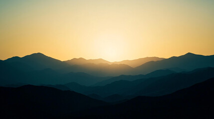 Fototapeta premium A scenic view of layered mountains under a warm sunset sky with soft light and distant peaks