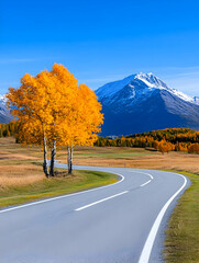 Scenic autumn road curving past golden aspen trees towards snow-capped mountains under a vibrant blue sky