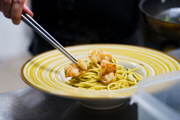Chef plating shrimp pasta with precision