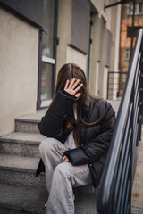 Stylish young woman in a black jacket on a city street on a cool day