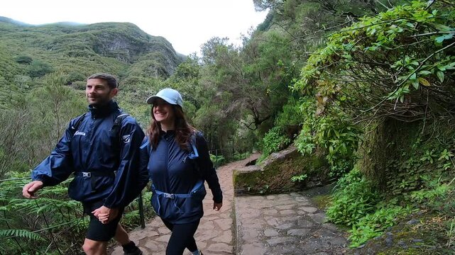 Couple hiking hand in hand along PR14 Levada dos Cedros through Madeira&rsquo;s lush Laurisilva Forest