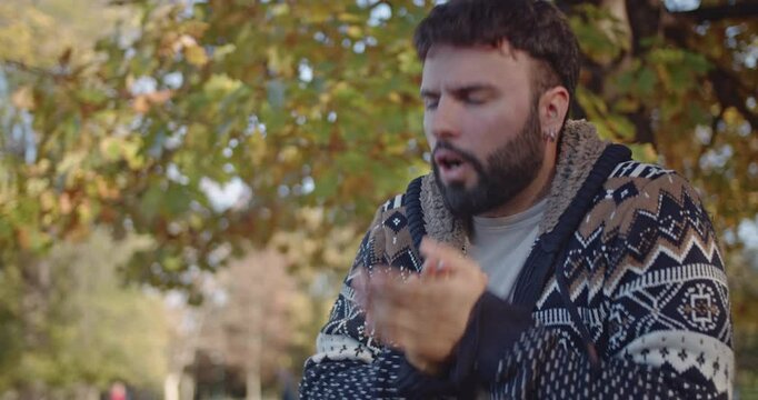 A young man experiences a range of emotions, from cold and shivering to happy and joyful, while spending time in a park during autumn. His facial expressions shift dramatically throughout the scene.