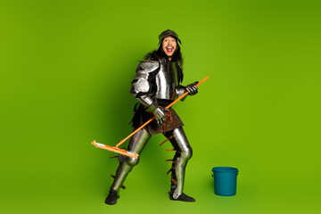 Naklejka premium Humorous depiction of a knight with a mop and bucket against a vibrant green backdrop