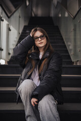 Fototapeta premium Stylish young woman in a black jacket on a city street on a cool day