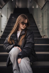 Stylish young woman in a black jacket on a city street on a cool day
