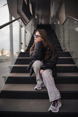 Stylish young woman in a black jacket on a city street on a cool day