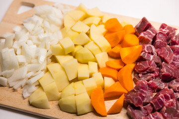 Fresh chopped onion potato carrot and beef on board