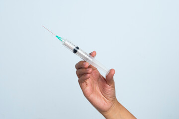 Asian woman's hand holding an injection on a white background. The hand holds a syringe.