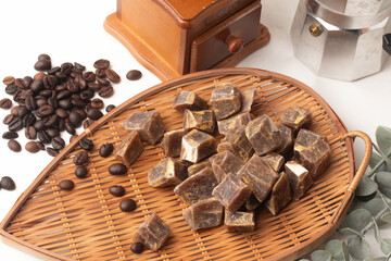 bamboo tray holds coffee flavored candies surrounded by coffee beans, manual coffee grinder, and moka pot, creating cozy and aromatic atmosphere