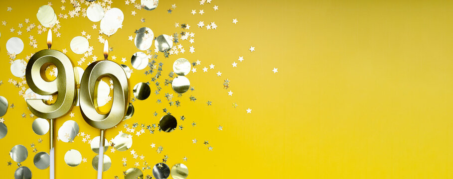 Ninety years birthday. Number 90 golden celebration candle. Yellow festive background. Concept of celebrating birthday or anniversary. Banner.