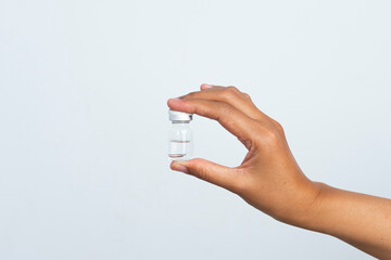 Blank Glass Medical Bottle mockup Isolated on White Background, Dropper Bottle Mock-Up - woman hands holding a dropper bottle on a gray background.
