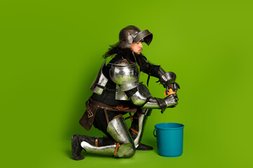 Young armored knight humorously performing chores against vibrant green background