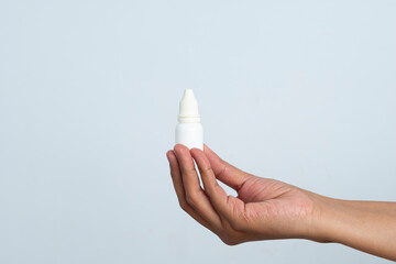 Woman holding a small medicine bottle with liquid eyes or ears drops. Close-up of medical container. Unscrewing bottle cap. Opening alergy fluid medicine. Liquid antibiotics. Health care product.