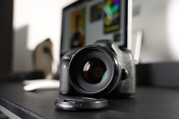 Professional camera and computer on black desk indoors, selective focus