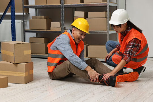 Accident at work. Woman helping her injured colleague in warehouse