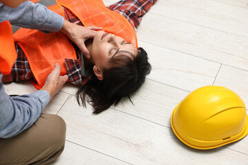 Accident at work. Man checking pulse of his unconscious colleague in warehouse, closeup