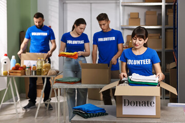 Group of volunteers packing donation goods at tables indoors