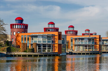 Barendrecht, The Netherlands, March 6, 2025: lakeside villas and residential "lighthouses" reflecting in a pond in Carnisselande neighbourhood