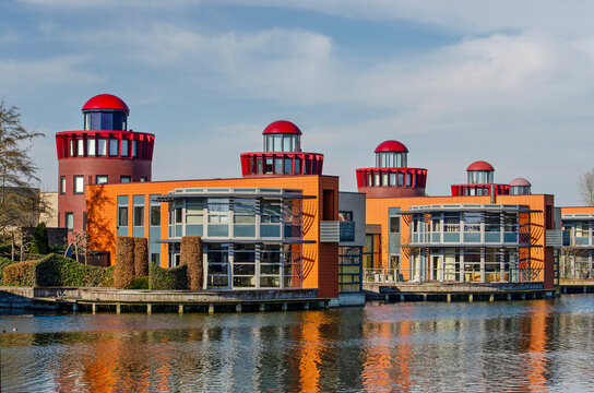 Barendrecht, The Netherlands, March 6, 2025: lakeside villas and residential "lighthouses" reflecting in a pond in Carnisselande neighbourhood