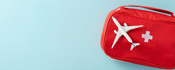 A red first aid kit placed alongside a miniature airplane, symbolizing travel safety