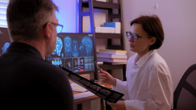 The doctor is analyzing and explaining an MRI scan to the patient to make a diagnose of brain conditions and prescribe a treatment in a medical hospital.