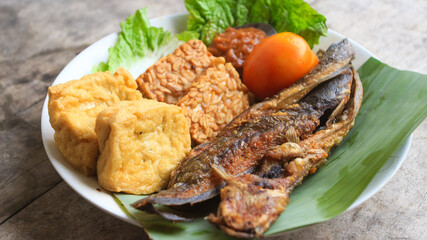 a plate of Fried Catfish with tomato sauce and fresh vegetables is a Traditional Indonesian Culinary Food. catfish pecel, suitable for menu catalogues, food recipe magazines and covers