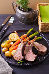 Roasted rack of lamb. Lamb chops with vegetables on black plate