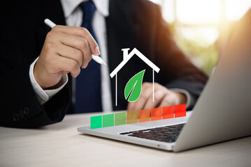 Sustainable housing concept with businessman evaluating energy chart on laptop, green building, environmental performance, smart eco home and clean energy design.